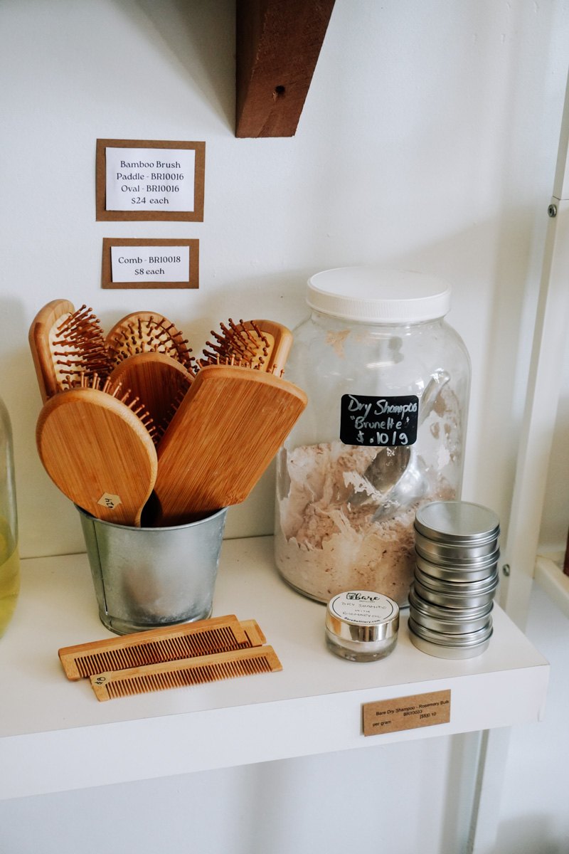 Bamboo hairbrushes, combs and dry shampoo on a white shelf