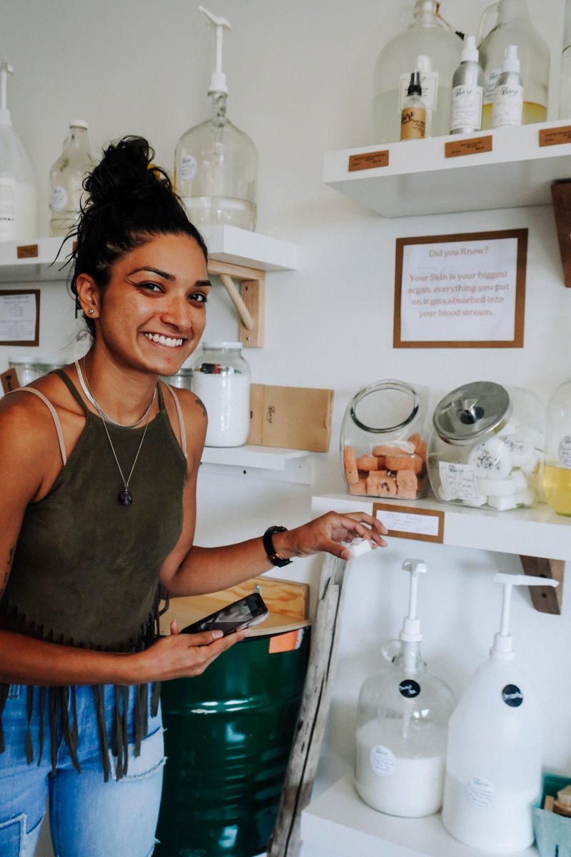 Smiling customer refilling a bottle at the Bare Refillery soap station