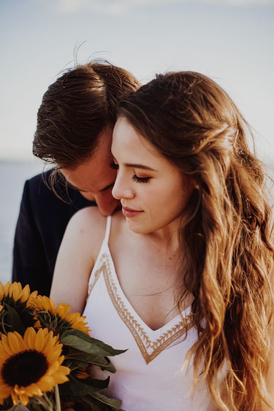 Couple embracing with sunflowers in soft window light