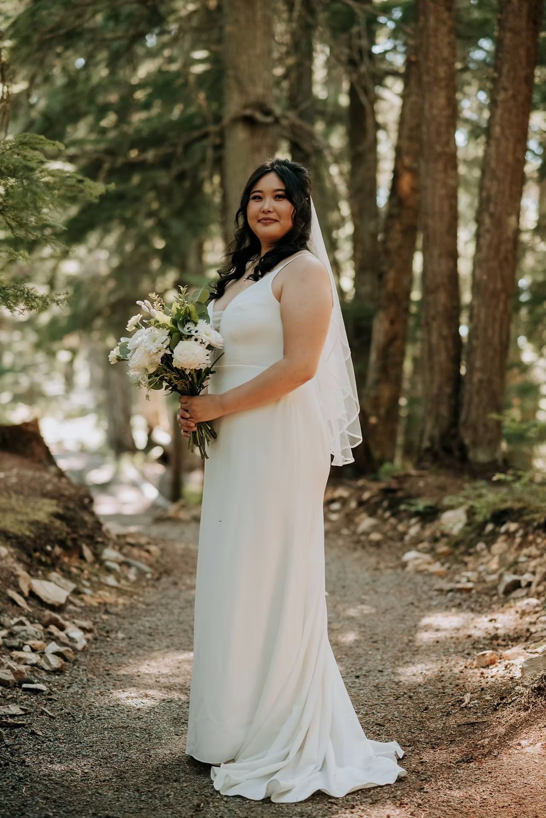 Bride holding a bouquet on a forest path