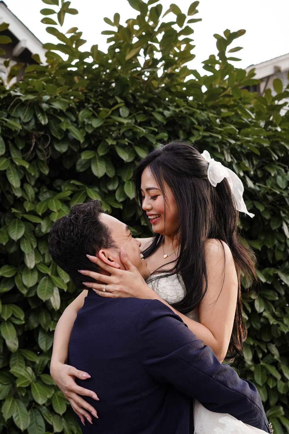 Couple embracing in front of a green hedge