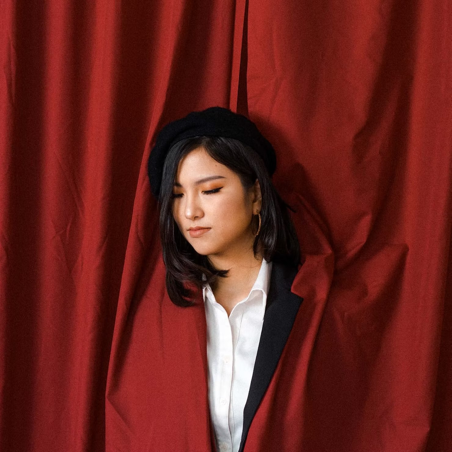 Portrait in a black beret and blazer against a red curtain