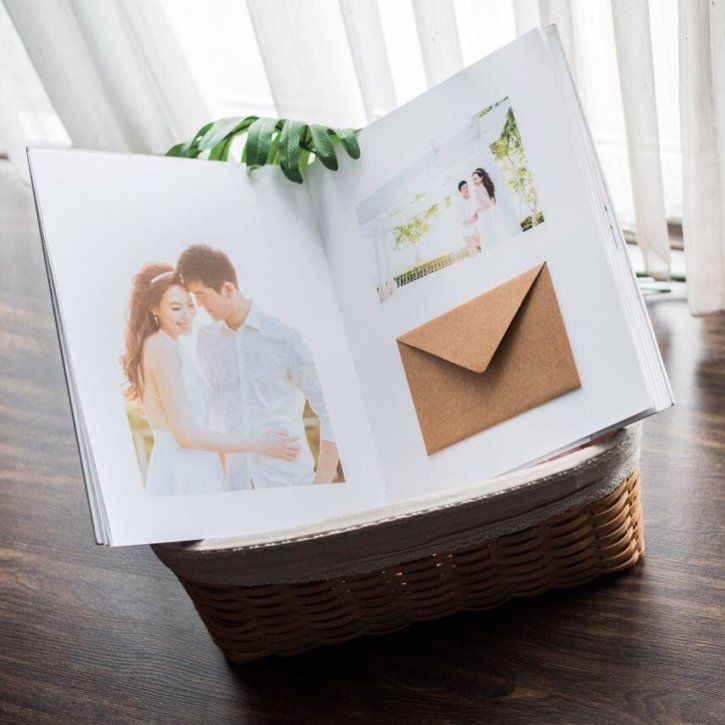 Open album with a kraft envelope insert resting on a woven basket