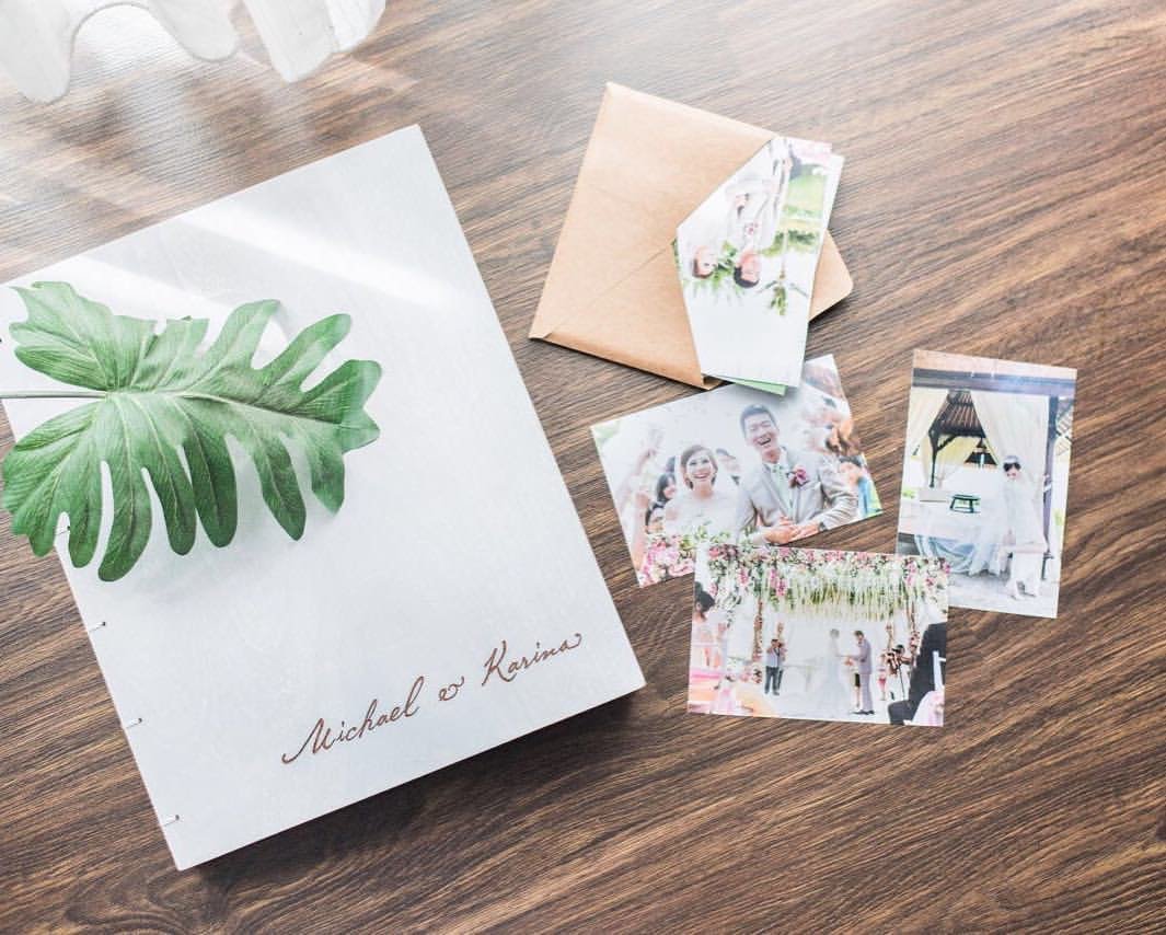 White album with calligraphy names, loose prints and kraft envelopes on wood