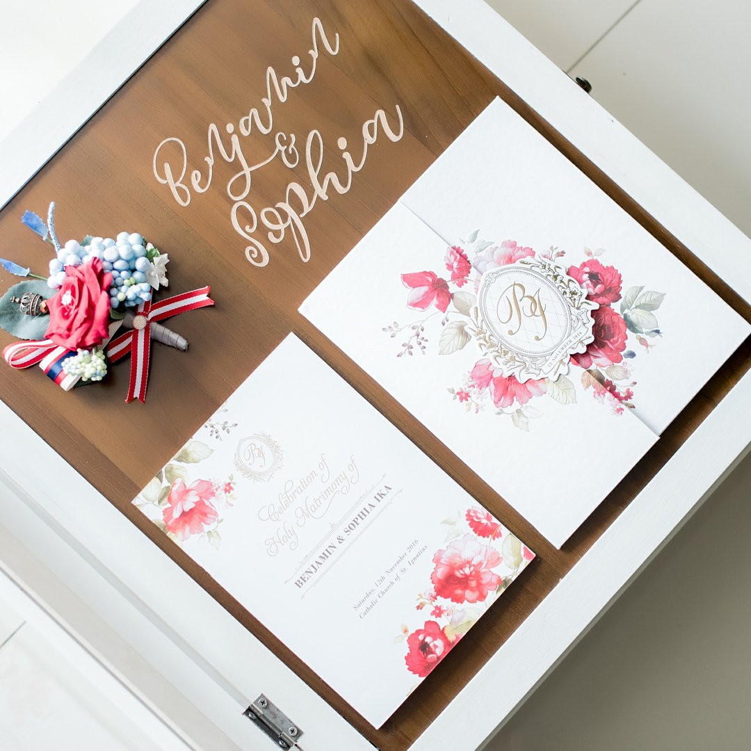 Wooden album cover with calligraphy names beside floral wedding stationery