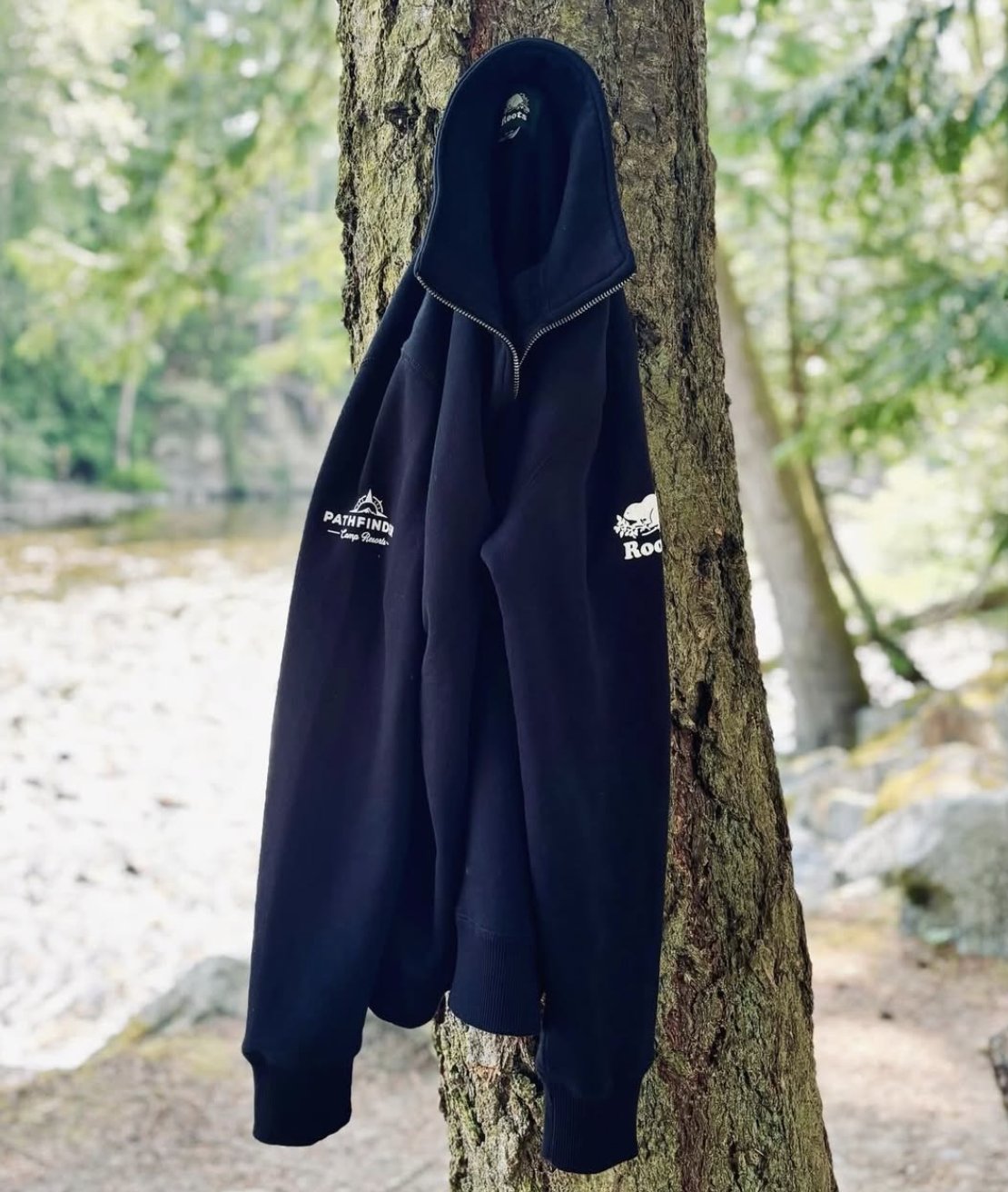 Pathfinder x Roots hoodie hanging on a tree by the river